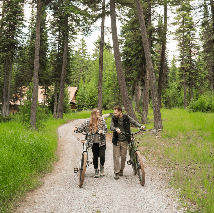 couples-bike-ride Couple walking their bikes on a path in the woods