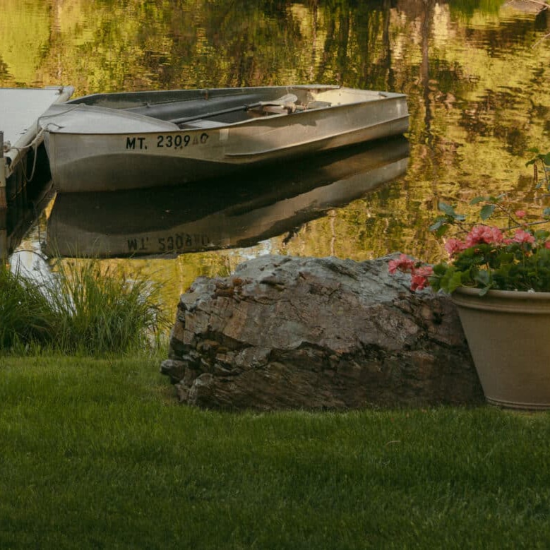 Golden-lit pond with dock and canoe at Mountainside Collective, luxury retreat destination in Whitefish Montana.