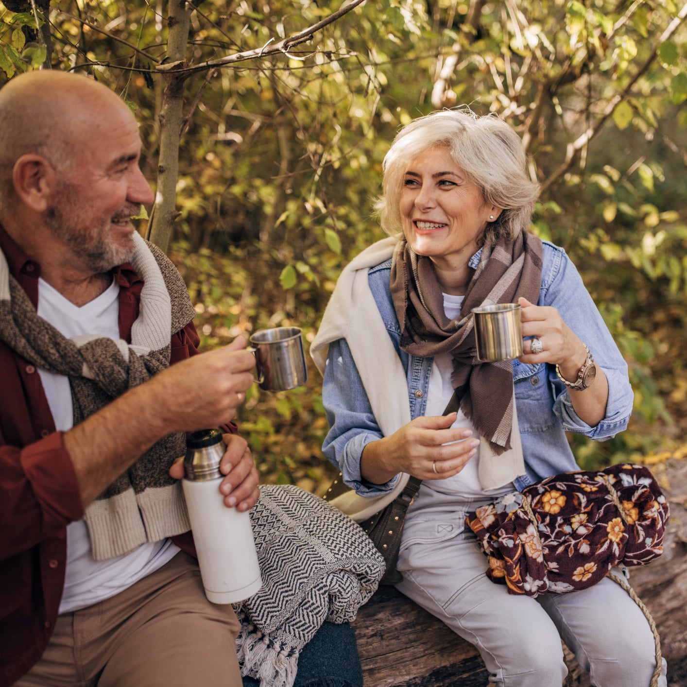 Older couple sitting on a log in nature enjoying a beautiful retreat in Whitefish Montana